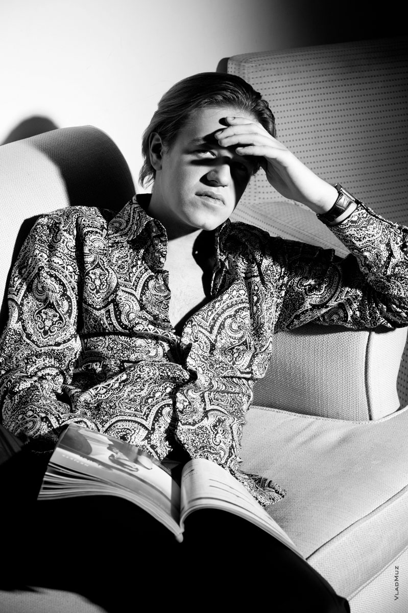 Фотопортрет мужчины на диване, читающего мужской журнал