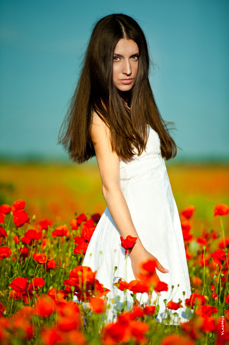 Фотография девушки-брюнетки в белом летнем платье на красном маковом поле