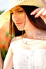 Летнее фото девушки в шляпе с солнечными бликами на лице сквозь шляпу