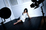 Фотография девушки-модели в интерьере студии, сидя на полу, после окончания фотосессии