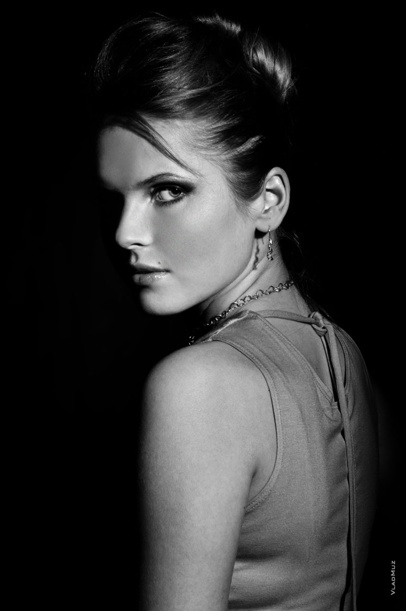 Модный черно-белый фотопортрет девушки на черном фоне с высоким контрастом