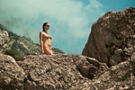 Фото девушки-модели в купальнике и солнечных очках на фоне горных пейзажей