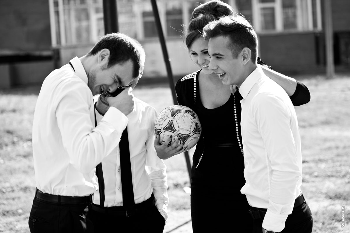 Фото смеющихся девушки-модели с футбольным мячом и мужчин