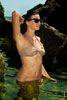 Фото девушки в купальнике и солнечных очках в воде на фоне камней