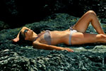 Фото загорающей на морском берегу девушки в купальнике и в солнечных очках